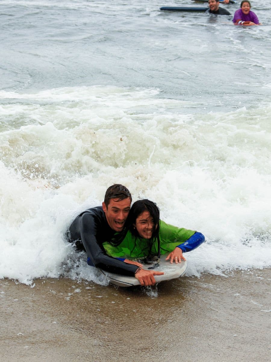 Estudiante y voluntario en una tabla de bodyboard entre las olas